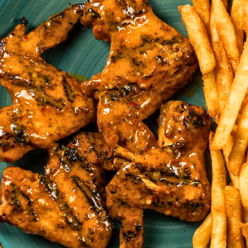 Grilled chicken wings served with seasoned rice at La Peri Peri Sterling Heights