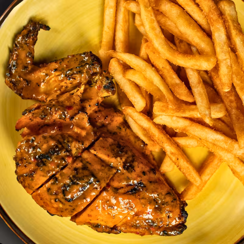 Grilled 1/4 chicken breast and wing served on a plate at La Peri Peri in Sterling Heights, MI