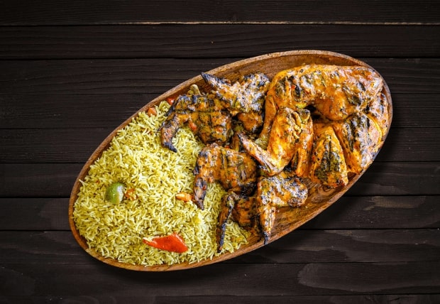 Boneless chicken fillets and peri tenders with rice, salad, and side served on wooden plate at La Peri Peri Sterling Heights
