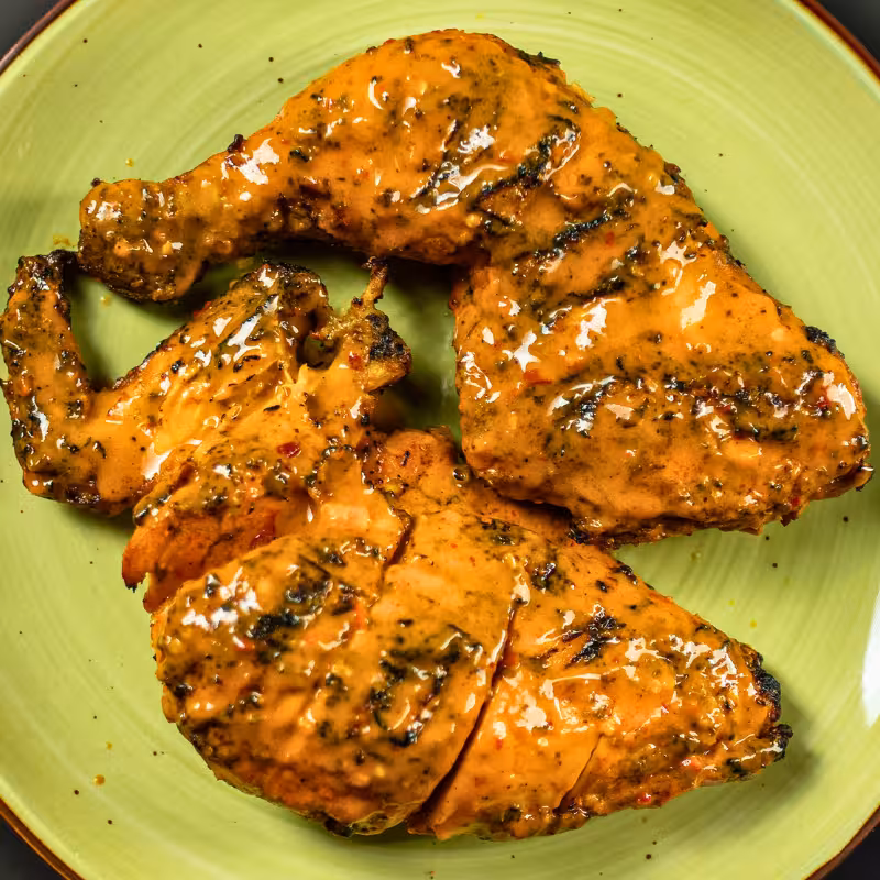 Flame-grilled Zabiha Halal 1/2 chicken with seasoned rice on a blue plate at La Peri Peri in Sterling Heights, MI