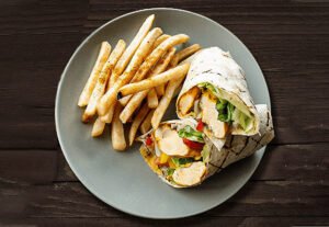 Zabiha Halal chicken wrap filled with lettuce, tomato, cucumber, jalapeños, and garlic sauce served with fries at La Peri Peri in Sterling Heights