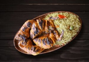Full Zabiha Halal grilled chicken served with rice and sides on a wooden platter at La Peri Peri in Sterling Heights, Michigan